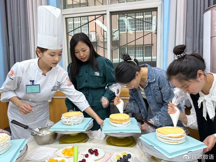 社区“宝妈”在烘焙师指导下为蛋糕胚涂奶油。（新华社记者 冯家顺 摄）