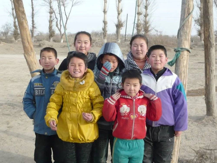 民勤煌辉村的孩子们最后一次在村里秋千下合影。/王文明 摄