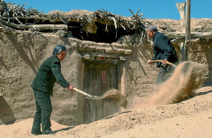 每次沙尘暴过后，宋和村的陈国兴和老伴就要清理门前的沙堆。王文明 摄