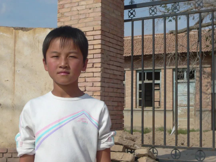 何芳菲换了四所学校，这是她在已废弃的煌辉小学门口的留影。王文明 摄