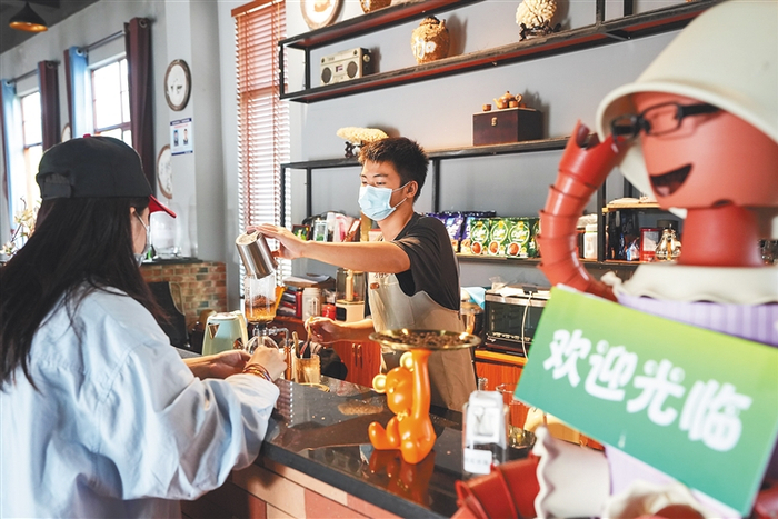 资料图：在澄迈县大丰镇才存村共享农庄的才存咖啡馆，咖啡师为游客现场制作咖啡。