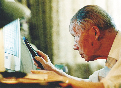 ▲在放大镜的帮助下，张光斗使用电脑工作。