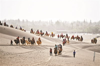 载着游客的驼队行走在鸣沙山月牙泉景区供图/新华社