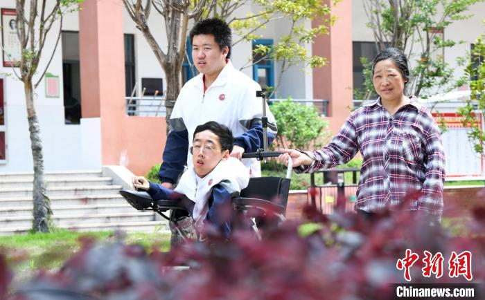 碰上天气好，朱金祥就会利用休息时间，和钟华强母亲将其推出来赏赏花，晒晒太阳，呼吸一下外面的新鲜空气。 卓忠伟 摄