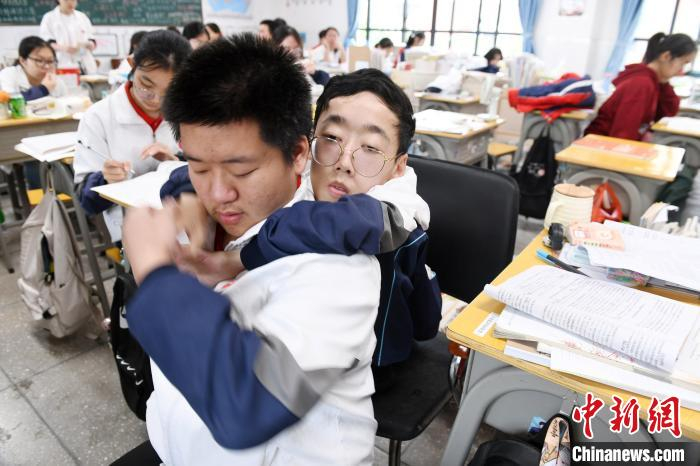 朱金祥（前左）和以往一样，正背着钟华强（前右）来到教室上课。 卓忠伟 摄