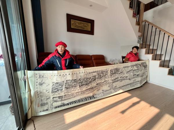 2021年，刘老和老伴展示《顾村老街荻泾河风情图》原稿。 吴越 摄