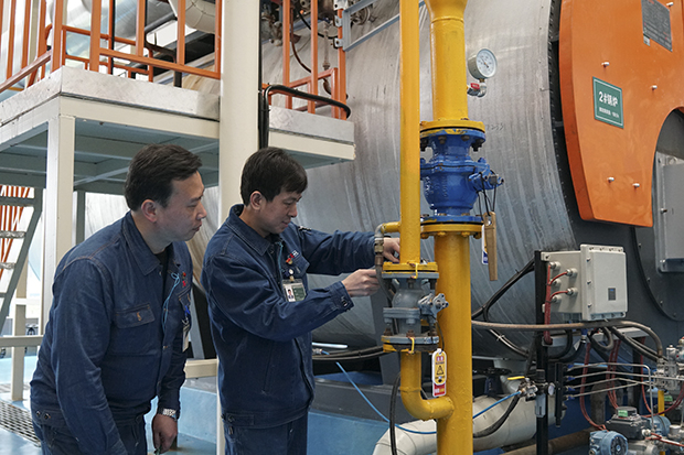 图为动力车间电工根据能源消耗数据检修锅炉