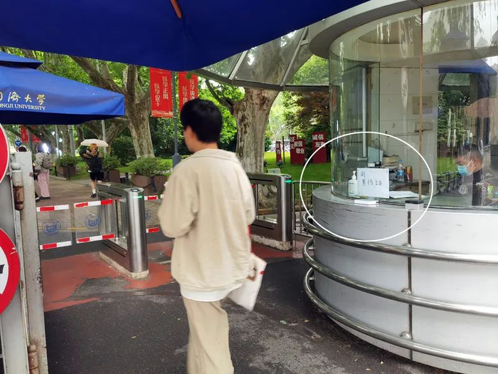 △同济大学四平路校区门卫室的窗户玻璃上贴有一张白纸，提示访客在下方的设备上刷身份证登记信息。