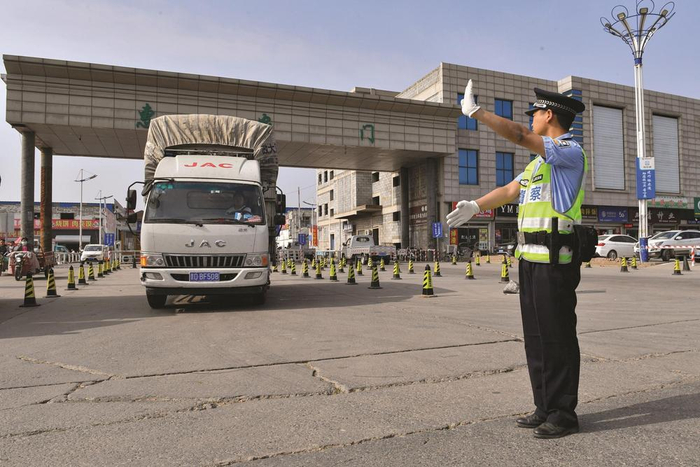         5月18日，邯郸交巡警在南大堡蔬菜批发市场指挥蔬菜运输车辆驶出市场。    本报记者 李磊 摄    