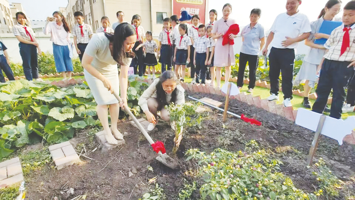     ▲南宁经开二小“和合红领巾生态园”开园，老师正给同学们做耕种示范    本报记者程勇可 摄