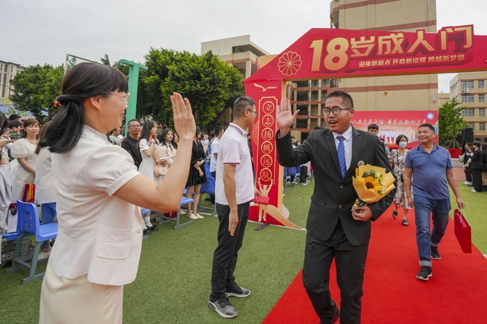 学生迈过成人门后和老师击掌鼓劲。通讯员 谢贵明 摄