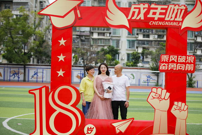 高三学生成人礼，学生和父母在标语框前一同合影。通讯员 谢贵明 摄