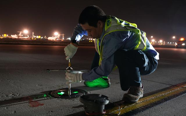 巡检过程中，董昊杰发现一盏助航灯灭了，拿出工具开始修理。新京报记者 王巍 摄