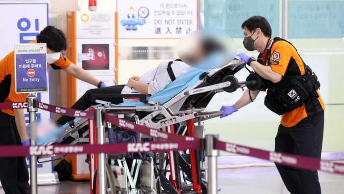 5月26日，在大邱国际机场，韩亚航空OZ8124客机因舱门打开事故紧急降落。图为乘客被送医。 图源：韩媒