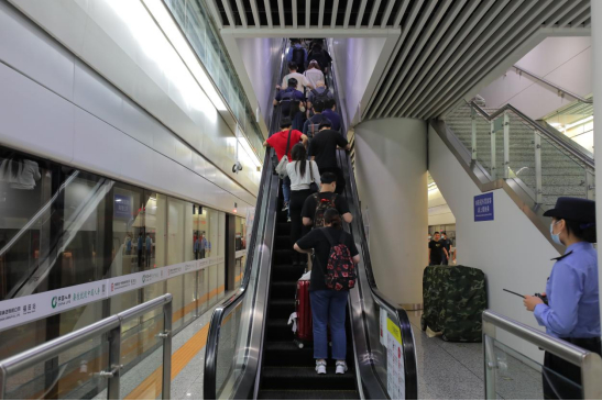 5月25日下午，在福田高铁站，到站乘客拖着行李搭乘同一部扶手电梯前往闸机出口。（图片由刘茜摄）