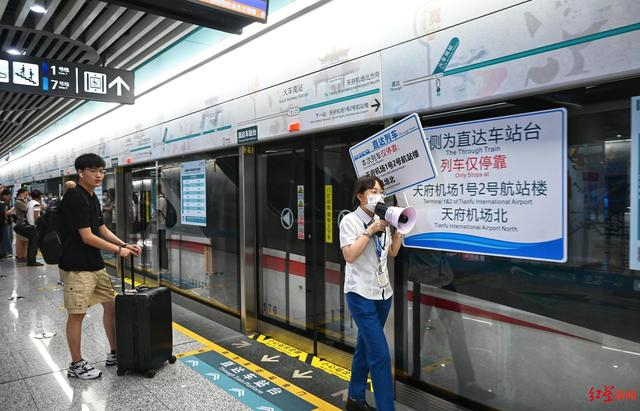 ▲地铁站台工作人员手持提示牌指引旅客乘车