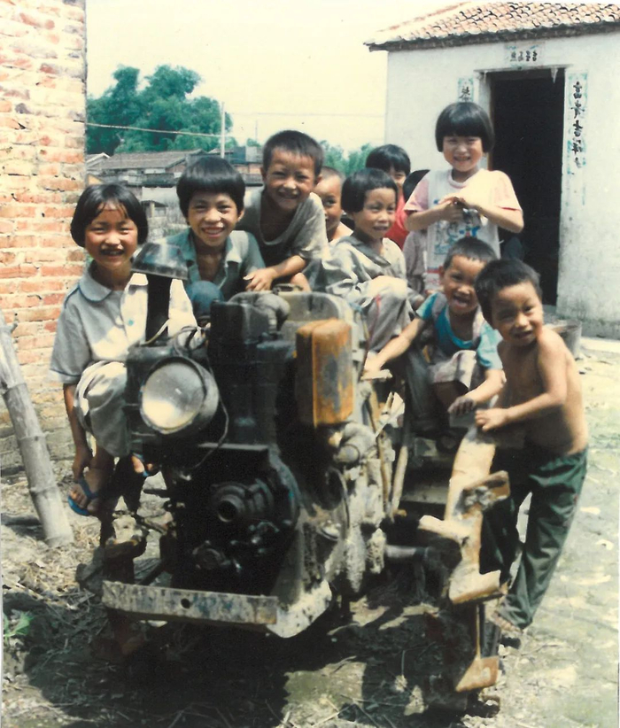 1995年，清新县太平镇大良管理区移民村，没见过拖拉机耕田的儿童要求和手扶拖拉机合影。（摄影：潘伟）