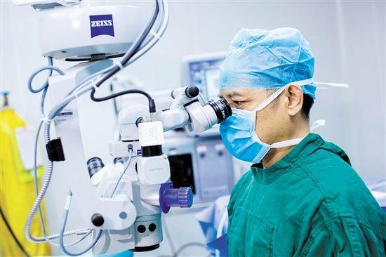 白内障患者应尽快手术。图为赵春阳在显微镜下给患者做手术。