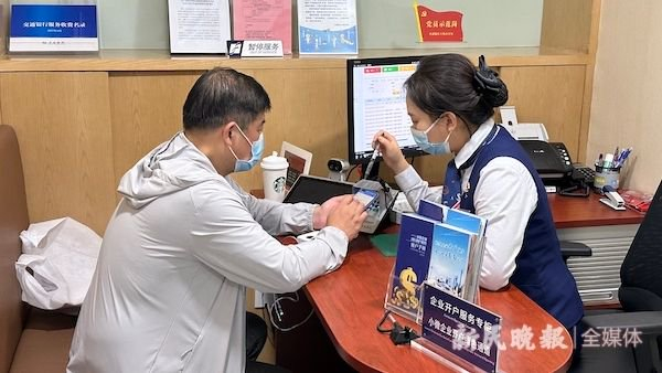 图说：尹先生在交行工作人员指导下，登录小程序办理企业银行账户开户 金旻矣 摄