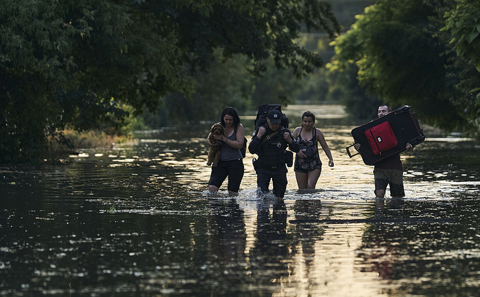 当地时间2023年6月6日，赫尔松地区，人们带着财物从被洪水淹没的地区撤离。