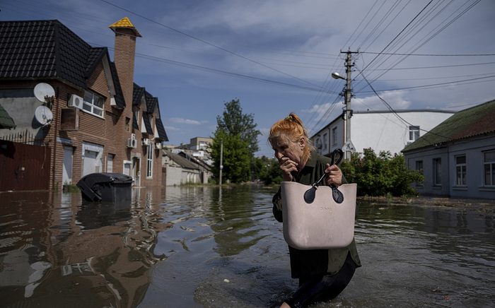 当地时间2023年6月6日，赫尔松地区，当地道路被洪水淹没，居民涉水前行。