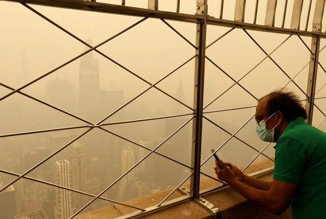 当地时间2023年6月8日，美国纽约，天空中笼罩着薄雾，滚滚浓烟飘进城市，人们开始戴上口罩，采取预防措施。图/视觉中国