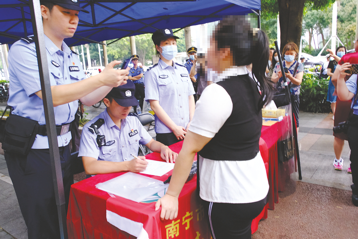     ◀在南宁市二十六中考点门口的护考服务点，新城派出所民警为一名考生办理临时身份证明    本报记者 宋延康 摄