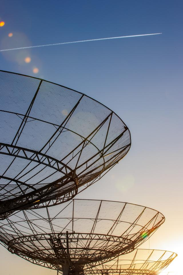 3月27日黄昏，国家天文台密云观测站，一架飞机飞过射电望远镜。新京报记者 王子诚 摄