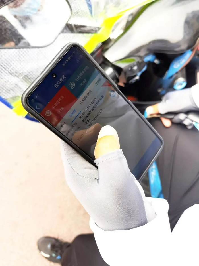 △一名“饿了么”骑手打开了手机中的“上海交警”App，向记者展示他5月份被拍下的3次违法行为。