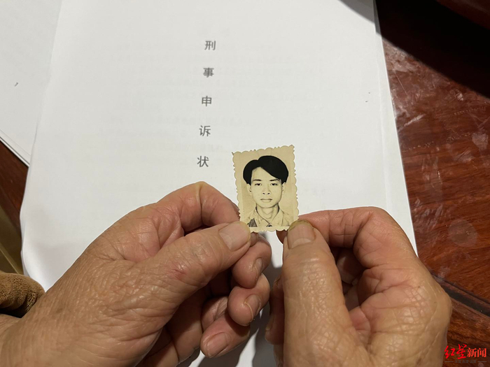 ↑梁志林母亲手持儿子遗照