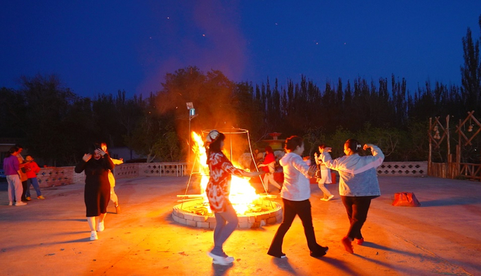 ▲民宿内，各地游客手牵手跳起欢快的麦西来甫。（摄影：施安）