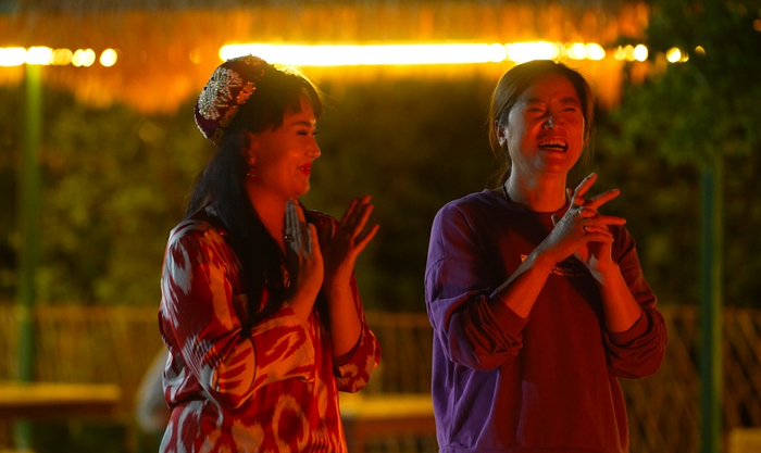 ▲民宿老板娘薛高飞（右一）带着游客跳起麦西来甫。（摄影：施安）