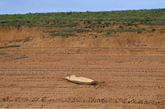 ↑当地时间2023年6月13日，越南安沛，Thac Ba水电湖内形成的一个岛屿上的一艘废弃船只。图据视觉中国