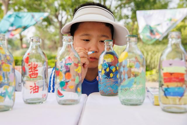 推广零碳，在瓶子上作画。新京报记者 王子诚 摄