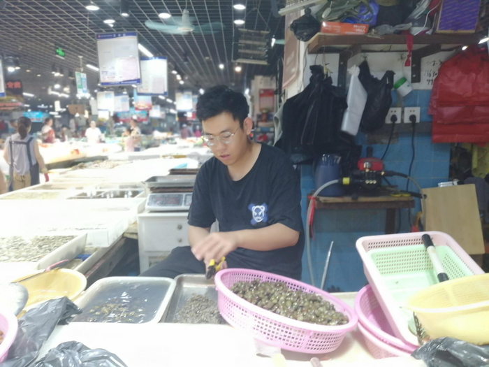 摊主告诉记者，把田螺尾部的尖儿剪掉，可以慢慢排出螺壳里的泥沙和杂质。李建/摄