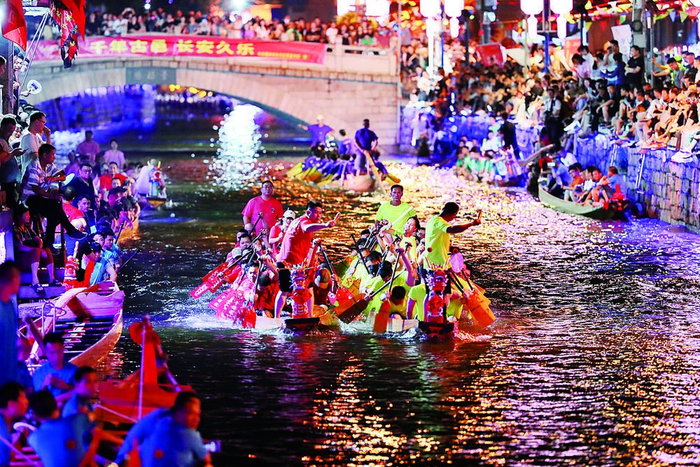     福州市长乐区三溪村，观众在小溪边观看龙舟夜渡迎端午活动。