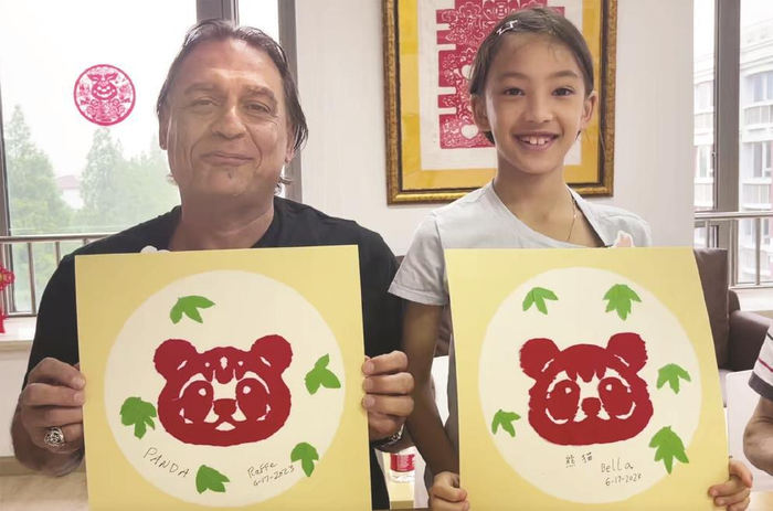 ▲沃尔夫父女展示自己创作的大熊猫作品。