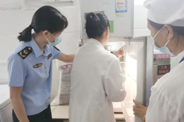 南雄市市场监管局执法人员在南雄中学食堂检查食品留样情况。