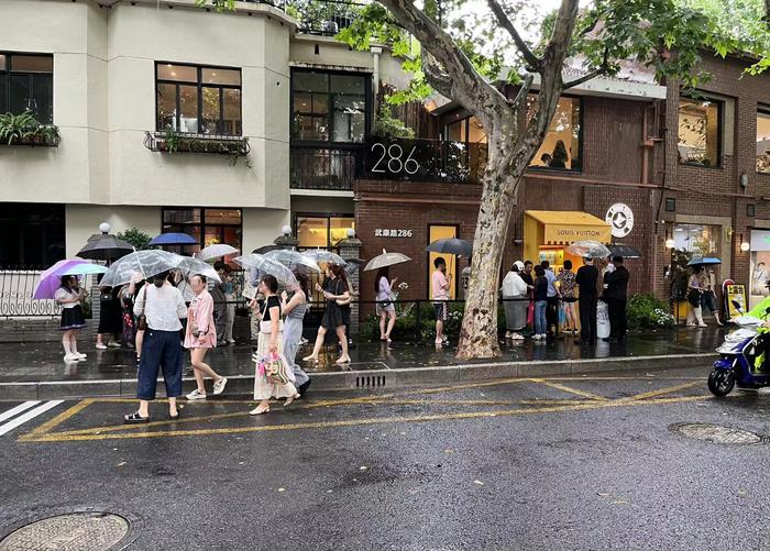 ↑门店外，东说念主们在雨中排起了队