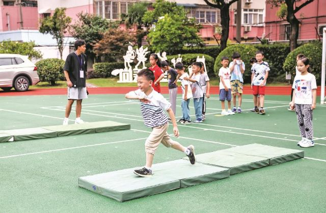 在徐汇区虹梅街道爱心暑托班办班点，小朋友在操场上参加体育活动。记者袁婧摄