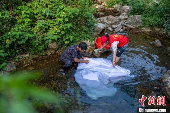 老人和义工一起洗幕布。章毅 摄