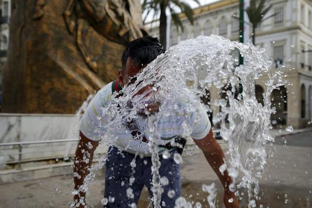 ▲7月10日，一名男子在阿尔及利亚首都阿尔及尔一处喷泉戏水消暑。图片来源/新华社