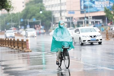 7月12日，白云路上，市民穿着雨衣在雨中骑行。 新京报记者 王飞 摄