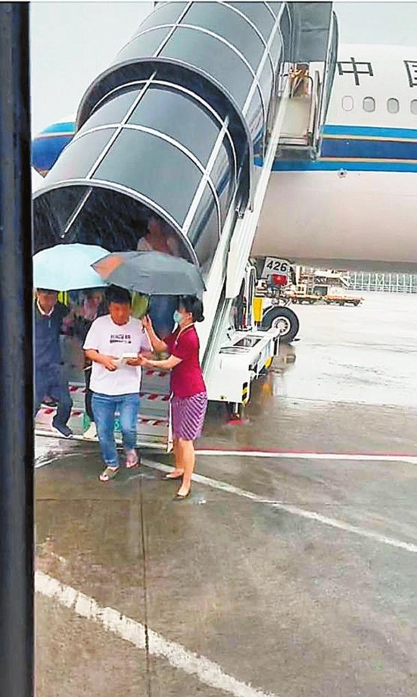 ▲南航空姐冒雨蹚水撑伞护送旅客下机获赞。