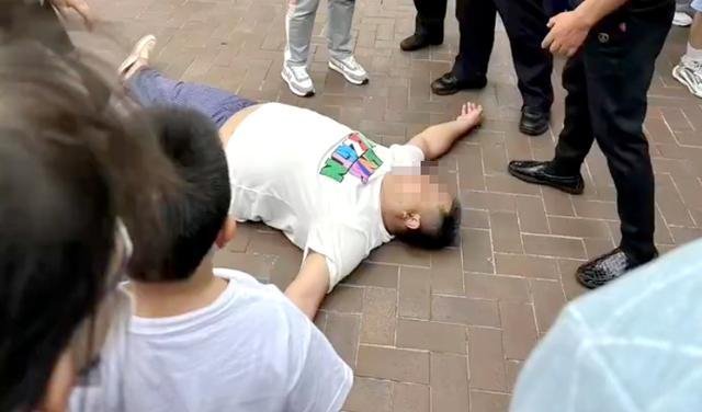 ▲一男子与迪士尼工作人员起冲突，看到民警到来就躺地上。  图片来源/网络