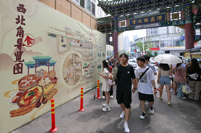 7月11日，在天津市红桥区西北角，人们走过在入口处设置的西北角美食导览图。新华社记者 孙凡越 摄