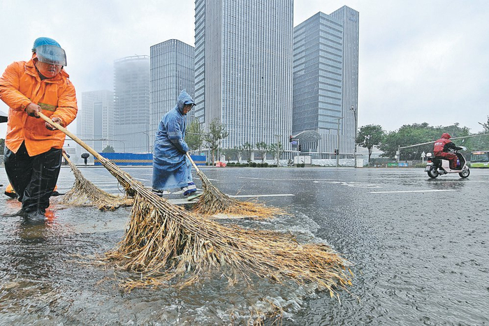 昨天上午，京环公司城市清扫二中心环卫工人在通州区东关大桥西侧，冒雨清理积水，保障行人与车辆安全。本报记者 白继开摄