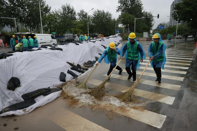 工人在堤坝前清扫积水。新京报记者 王子诚 摄