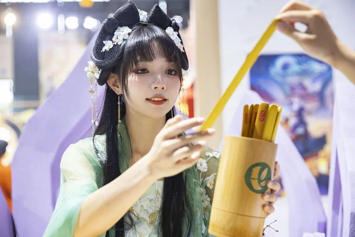 张欣羽抱着签筒，供漫迷抽签参与展台的互动体验。