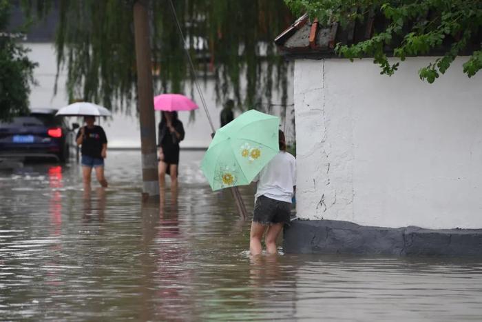 7月31日，市民行走在雨中的北京房山区瓦窑头村。中新社记者 崔楠 摄